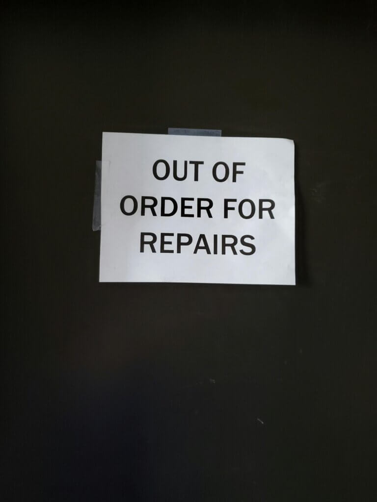 Close-up of an 'Out of Order for Repairs' sign on a wall, indicating maintenance.
