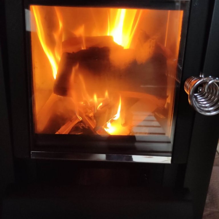 Sauna Innenraum mit Nahaufnahme vom Harvia Holzofen und loderndem Feuer