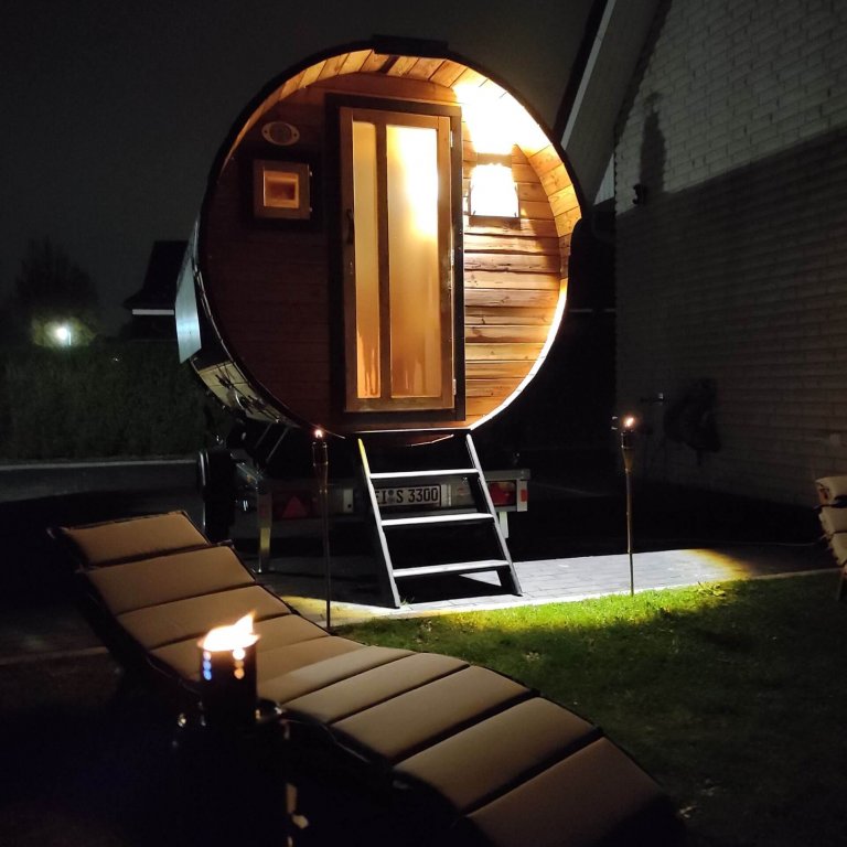 Sauna mit geschlossener Türe bei Nacht mit Fackeln und Wellness-Liegen