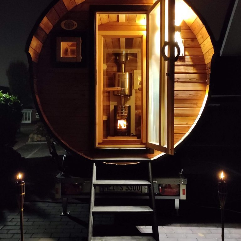 Sauna mit geöffneter Türe bei Nacht mit Fackeln